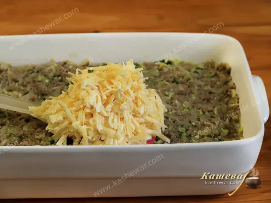 Grated cheese is laid out on top of minced meat