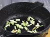 Кусочки зеленого лука в сковороде